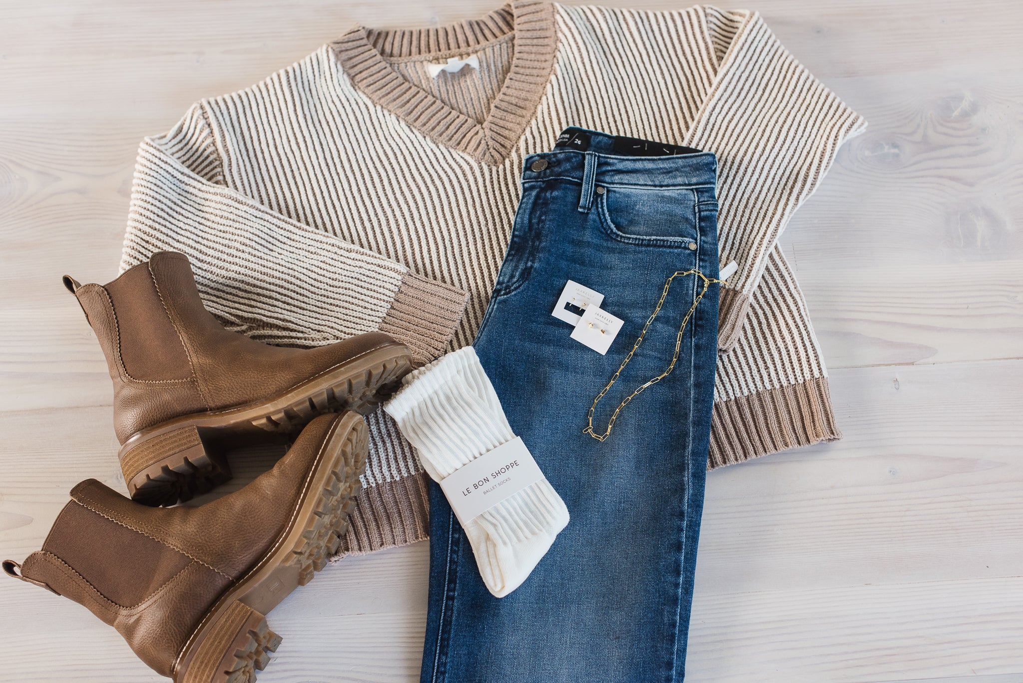 Sweater, jeans, and boots on a light wooden surface