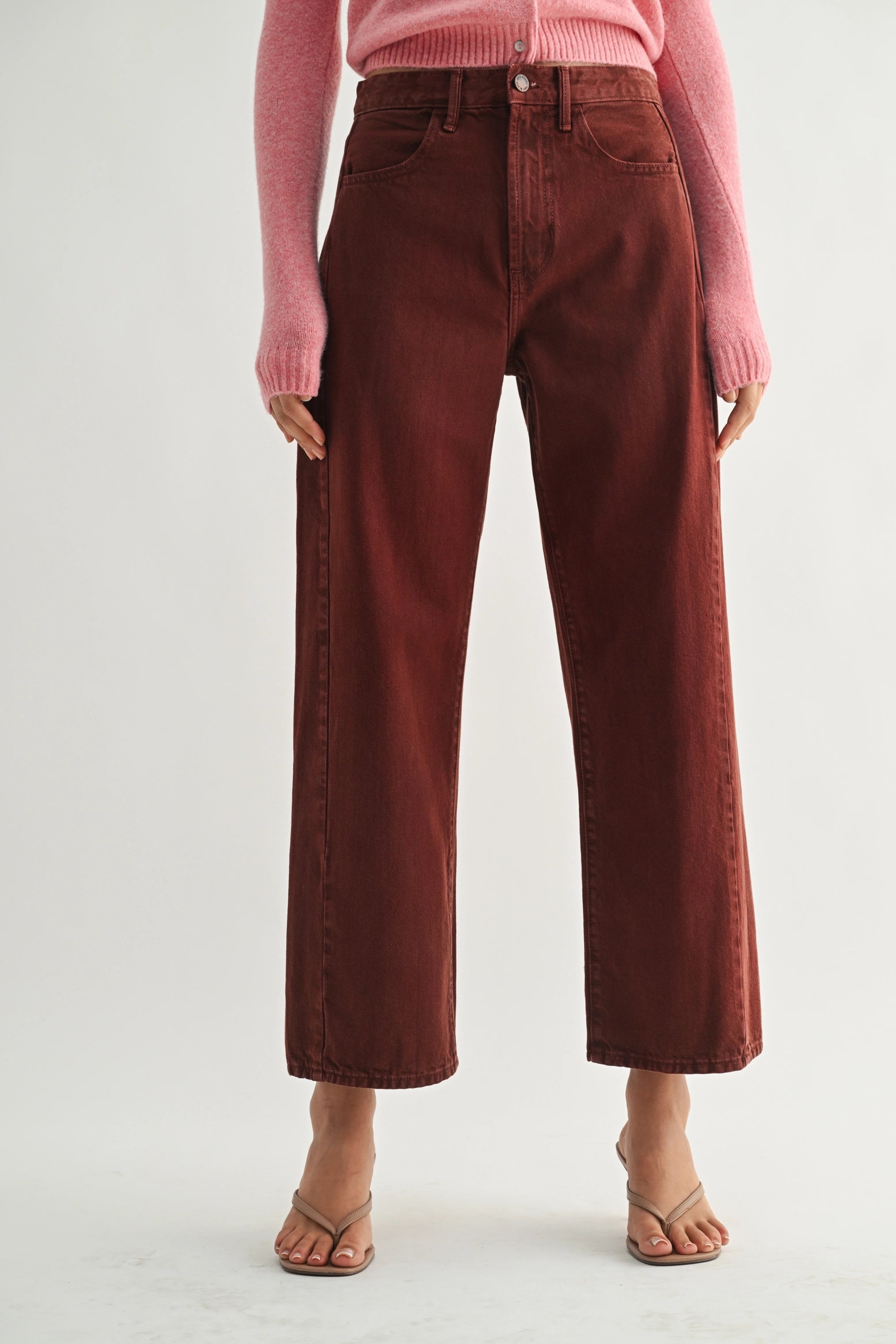 Person wearing maroon pants and a pink top on a white background